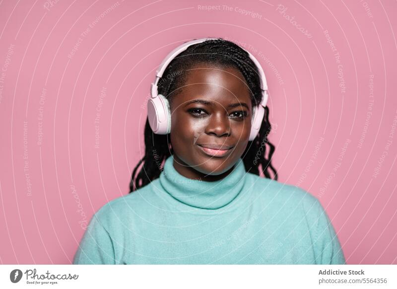 African woman with headphones african pink background close-up portrait music listener joy technology audio entertainment face expression calm wireless fashion