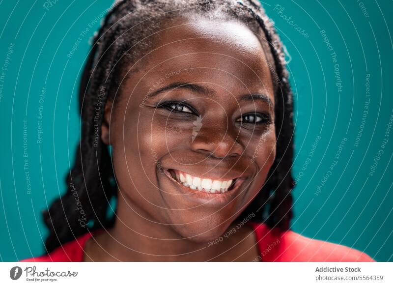African woman in red blouse african turquoise background braided hair neck portrait face beauty culture black female young adult melanin serious expression eyes