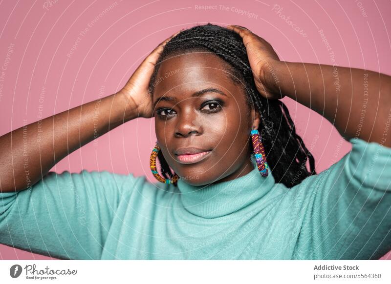 Portrait of African woman in turquoise sweater african braided hair earrings colorful pink background confident beauty fashion style portrait face close-up