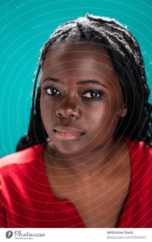 African woman's detailed eyes african close-up braided hair turquoise background beauty skin emotion expression gaze stare pupil iris eyebrow face makeup