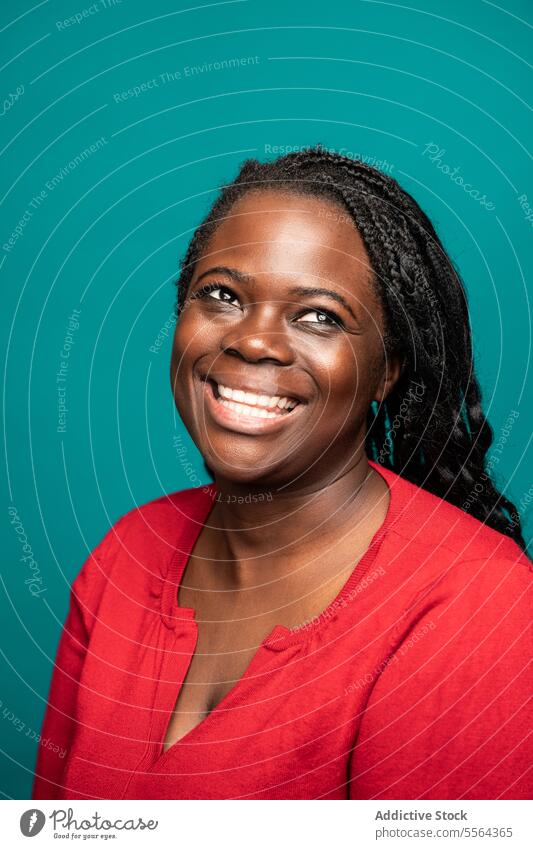 Joyful African woman portrait against teal background african smile joy braided hair turquoise face emotion happiness beauty female adult cheerful look glance