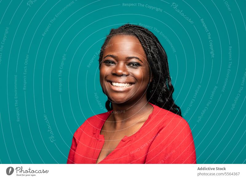 Close-up of cheerful African woman against teal background african close-up portrait smile braided hair red top eyes face skin beauty expression joy female