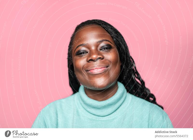 Portrait of joyful African woman against pink background african smile teal sweater happy face beauty emotion teeth expression makeup laugh eyes charm warmth
