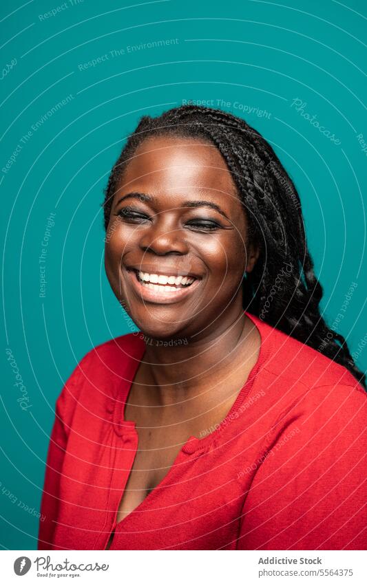 Warm smile of African woman against teal background close-up african red blouse warm eye teeth skin face beauty emotion happiness radiant gaze joy female adult