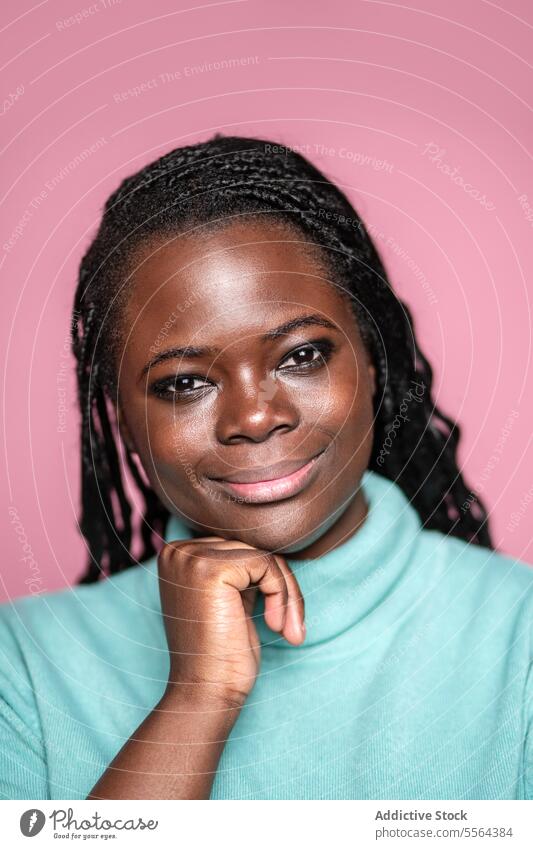 Smiling African woman in mint green turtleneck african smile pink background braids hair happiness beauty fashion portrait style gaze elegant makeup casual