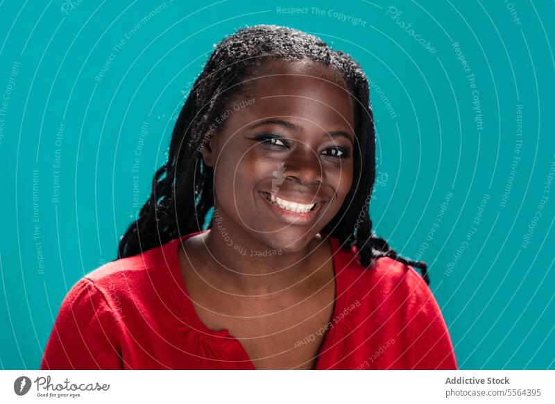 Radiant African woman in red against teal background portrait african smile radiant top turquoise beauty joy fashion expression close-up cheerful hairstyle