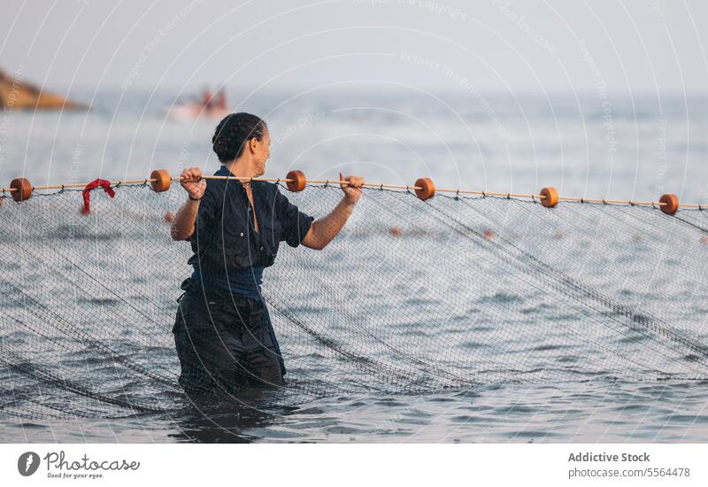 Happy young woman standing near fishing net in water in daylight smile sea rope ocean wet summer female daytime sun nature positive happy blue sky glad content