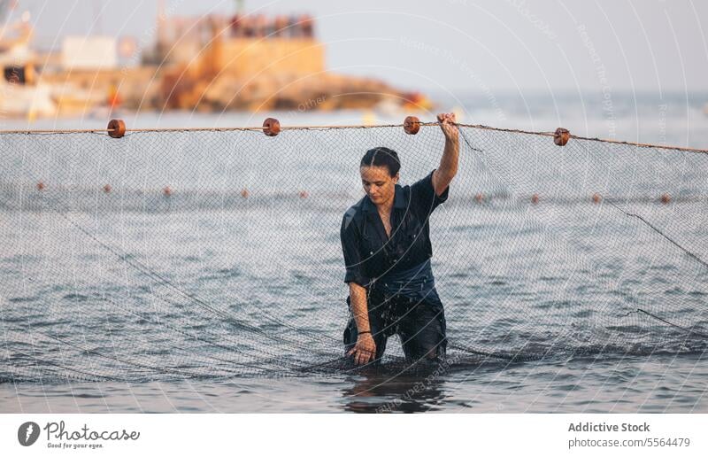 Serious young woman standing near fishing net in water in daylight sea rope ocean wet summer female daytime sun nature positive blue sky shore sunlight enjoy