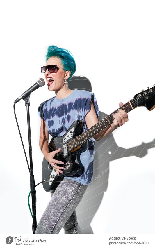 Energetic female rock star playing guitar in bright studio over white background woman musician perform style instrument thoughtful guitarist sing excited hobby
