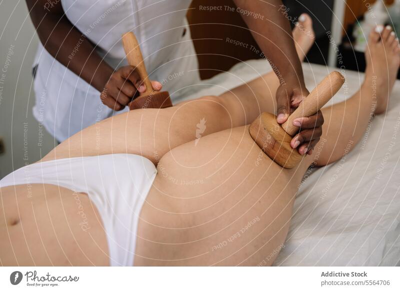 Crop masseur massaging leg of female patient massage wooden woman procedure physiotherapy treat wellness professional health care spa legs therapist