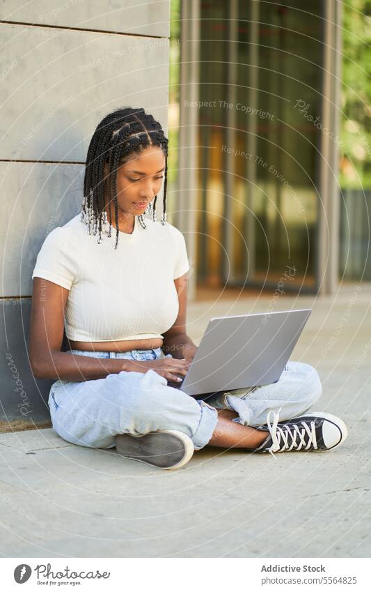 Focused African American woman using laptop while sitting on floor work freelance online surfing internet pc browsing focus businesswoman concentrate