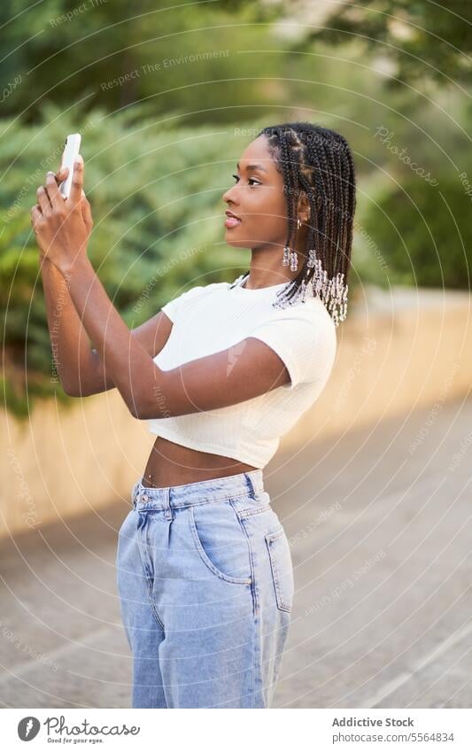 African American woman taking selfie on smartphone happy park take photo mobile using device tree cellphone moment bush social media memory self portrait stand