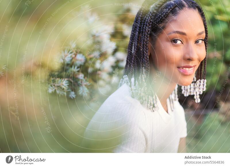 Smiling African American woman in blooming garden with flowers smile park blossom nature summer flora young casual sit relax braid style plant idyllic enjoy