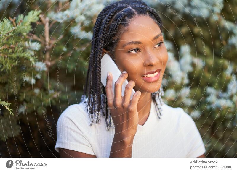 Delighted African American woman talking on smartphone in garden smile positive conversation speak phone call park mobile casual cellphone content optimist