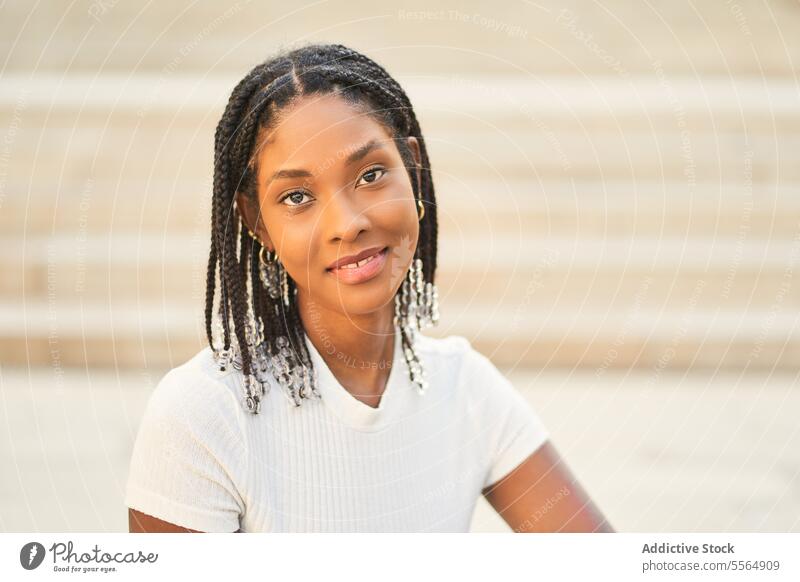 Smiling African American woman sitting looking at camera in stairs smile flora young casual relax braid style idyllic enjoy lifestyle peaceful happy positive