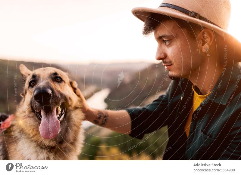 Dog with man at sunset in nature dog obedient loyal german shepherd animal owner male content lake domestic friend twilight sundown mammal friendship hat