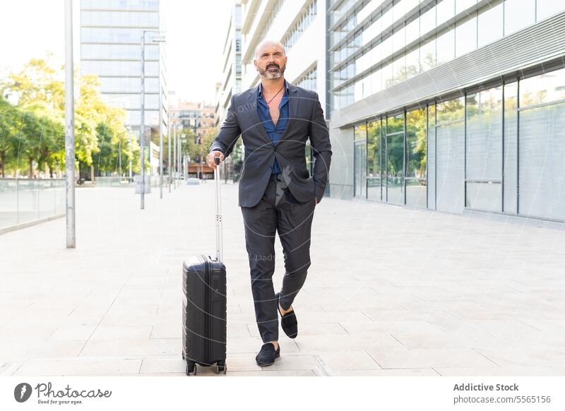Businessman walking down the street with his suitcase businessman person adult luggage business travel city street lifestyle outdoors day full length city life