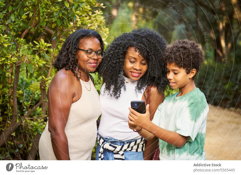 Outdoor moment with family sharing smartphone view woman boy outdoors engagement interaction park bench tree bonding togetherness connection screen child gaze
