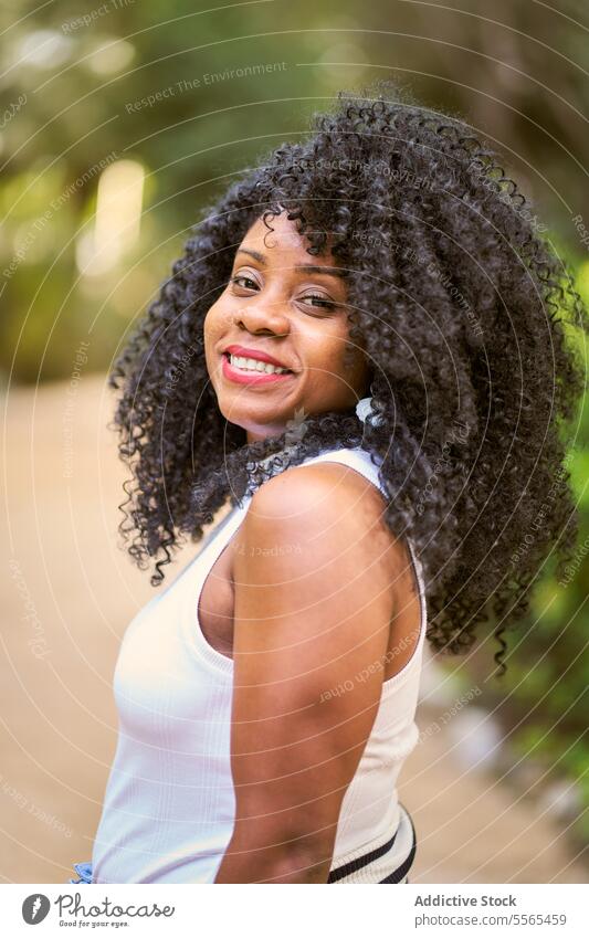 Radiant woman enjoying nature's beauty garden smile curly hair portrait African-American outdoors summer day fashion tree cheerful emotion green real people