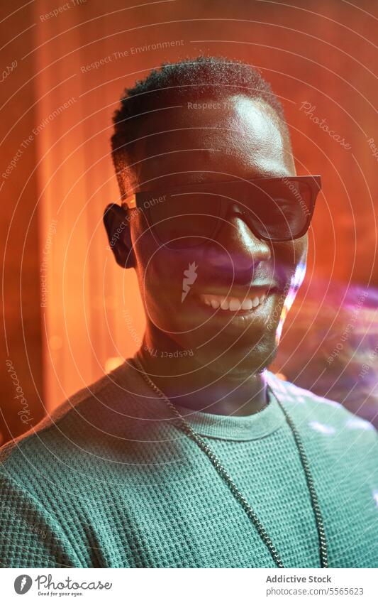 Stylish black man in orange light young stylish confident sunglasses trend happy haircut background modern fashion smile profile cheerful silhouette cool urban