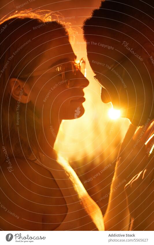 Multiracial couple at the disco multiracial close-up intimate gaze eyes fiery ambiance connection love emotion warmth touch woman dance sunglasses profile light