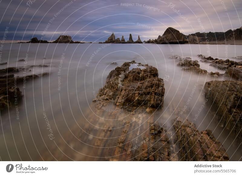 A long exposure of a beach with rocks in the water landscape sea coastline asturiana dusk serene tranquil nature photography ocean waves shore sunset scenic
