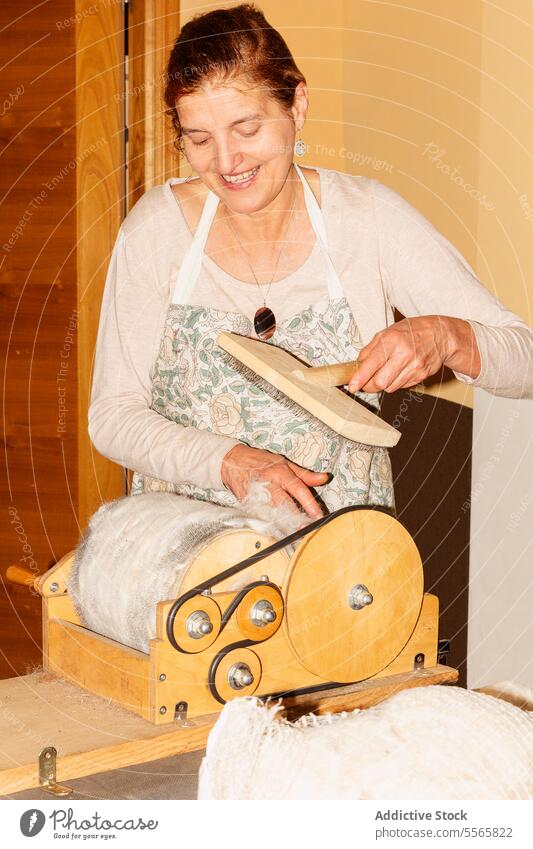 Title: Woman preparing wool with drum carder in bright room woman preparation spinning hand-operated smile work textile fiber craft equipment tool manual