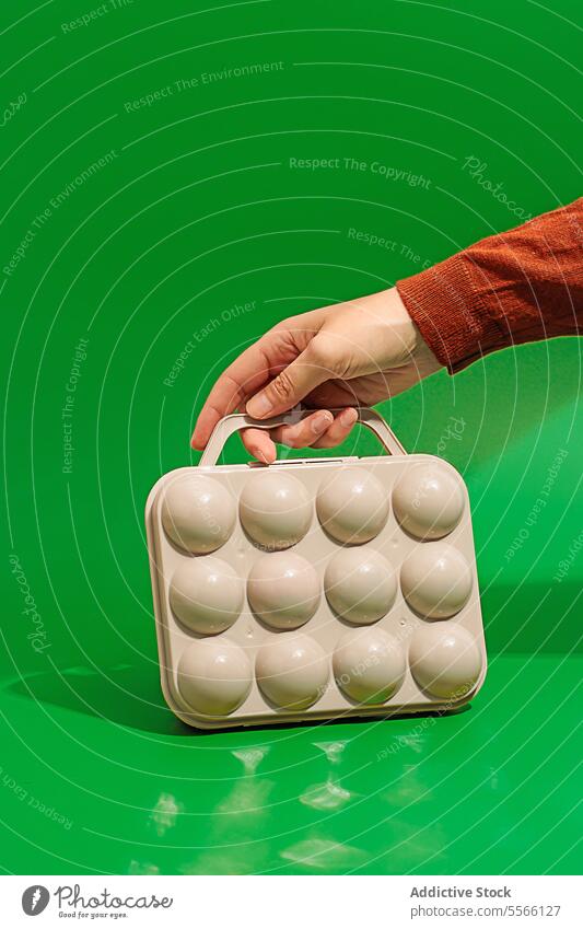 Crop person hand with golf balls box on green surface game sport plastic body part shape hold play show equipment sphere design color club ground crop object