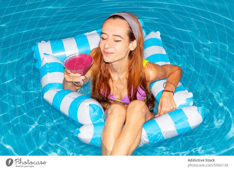 Woman in a sunny day relaxation in the pool with cocktail. woman summer drink inflatable raft blue water enjoying holiday vacation swim tan lounge refreshment