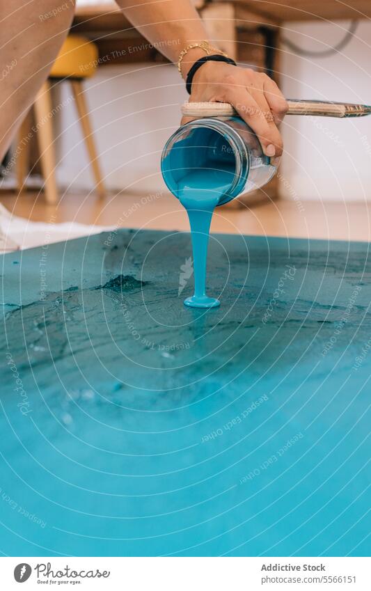 Crop artist painting on floor in room pour painter paintbrush acrylic liquid artwork blue craft skill process creative color faceless blur mix hand handicraft