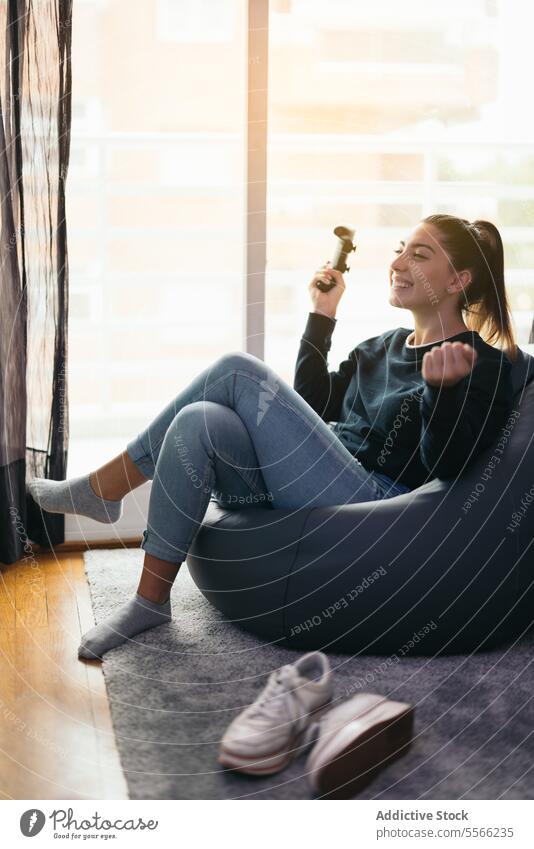 Cheerful woman with joystick the game at home pensive console using videogame shrug gesture bean bag female device young controller cheerful apartment lady