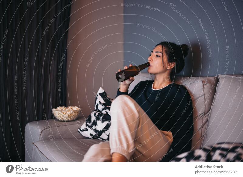 Young woman resting on sofa and drinking beer relax comfort bottle cozy living room at home female young chill weekend couch casual beverage apartment flat