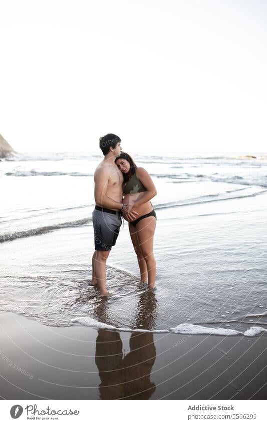 Man touching belly of pregnant woman on seashore couple sunset tummy together love pregnancy evening tender summer relationship harmony seaside sunlight
