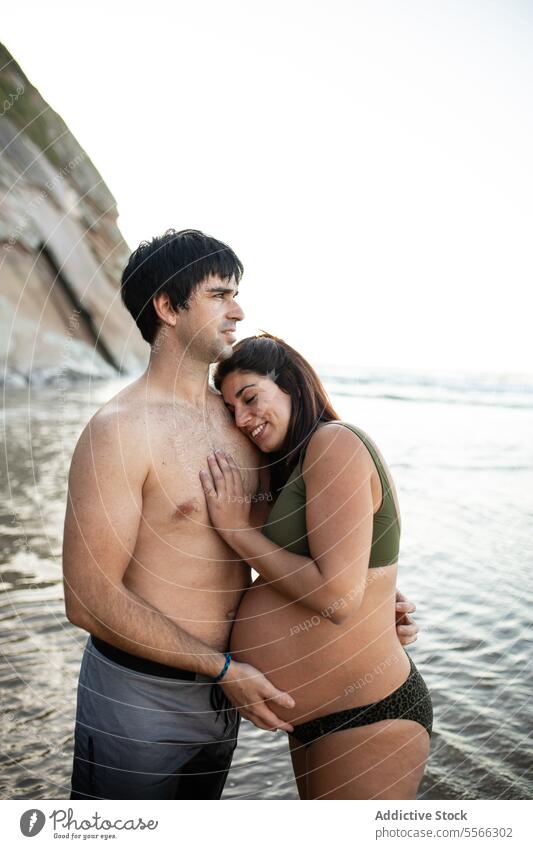 Man touching belly of pregnant woman on seashore couple sunset tummy together love pregnancy evening tender summer relationship harmony seaside sunlight