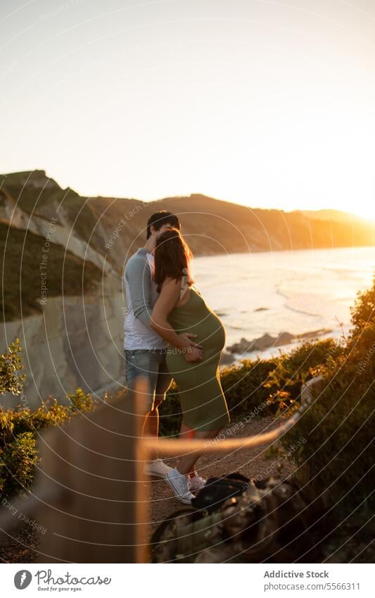 Anonymous pregnant couple hugging in nature pregnancy cliff love together relationship man woman relax summer rest belly romantic tender expect maternal