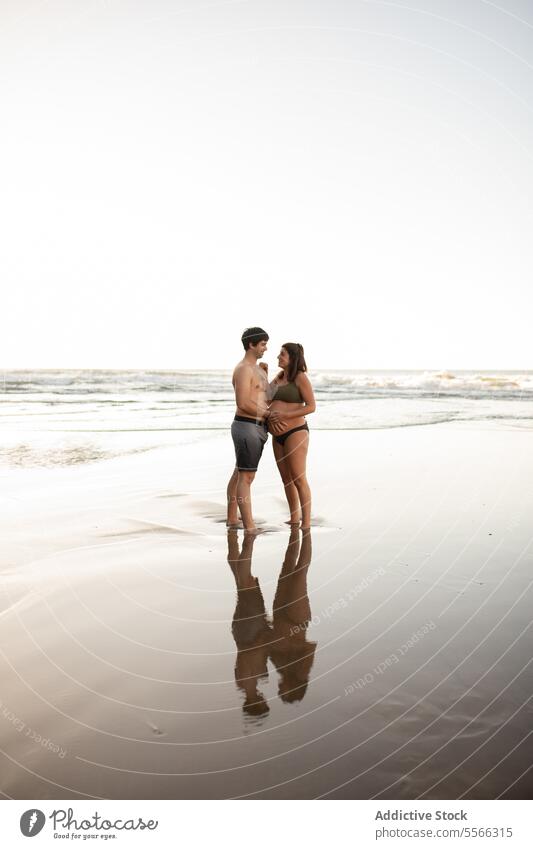 Smiling man touching belly of pregnant woman on seashore couple sunset tummy together love pregnancy evening tender summer relationship harmony seaside sundown