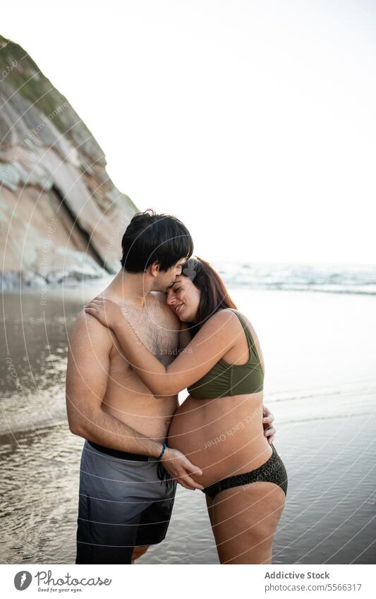 Man kissing and touching belly of pregnant woman on seashore couple sunset tummy together love pregnancy evening tender summer relationship harmony seaside