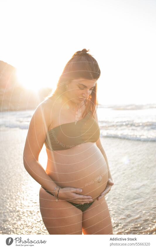 Pregnant woman standing in sea water pregnant belly expect bikini summer sunset await touch female happy cheerful smile prenatal anticipate pregnancy maternal