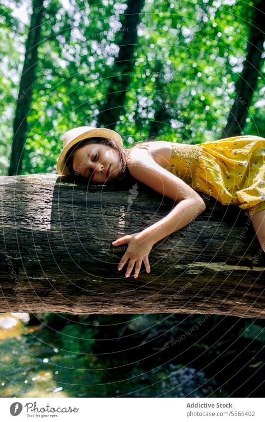 Preteen girl lying on tree trunk in nature forest tired relax explorer break recreation woods adventure tranquil enjoy peaceful summer harmony freedom journey