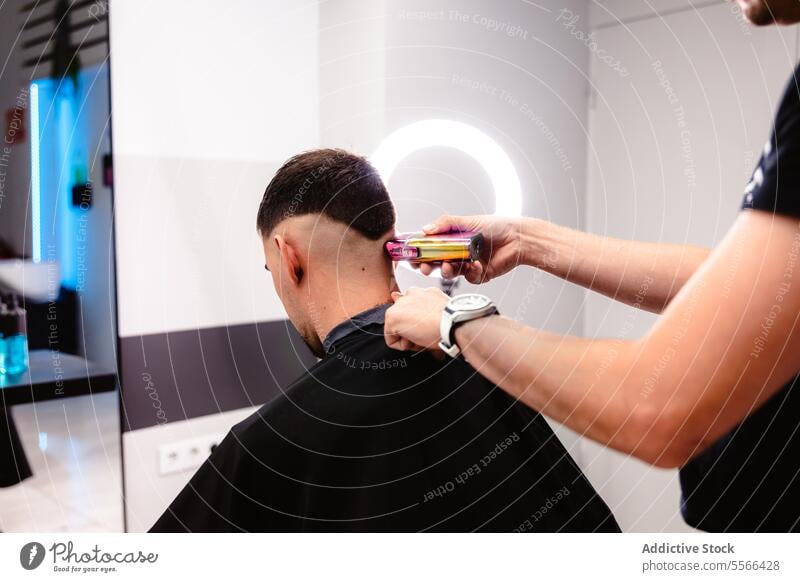 Barber's precision trim with electric clipper. client male cut salon short hair modern technique care styling professional man young barbershop hand equipment