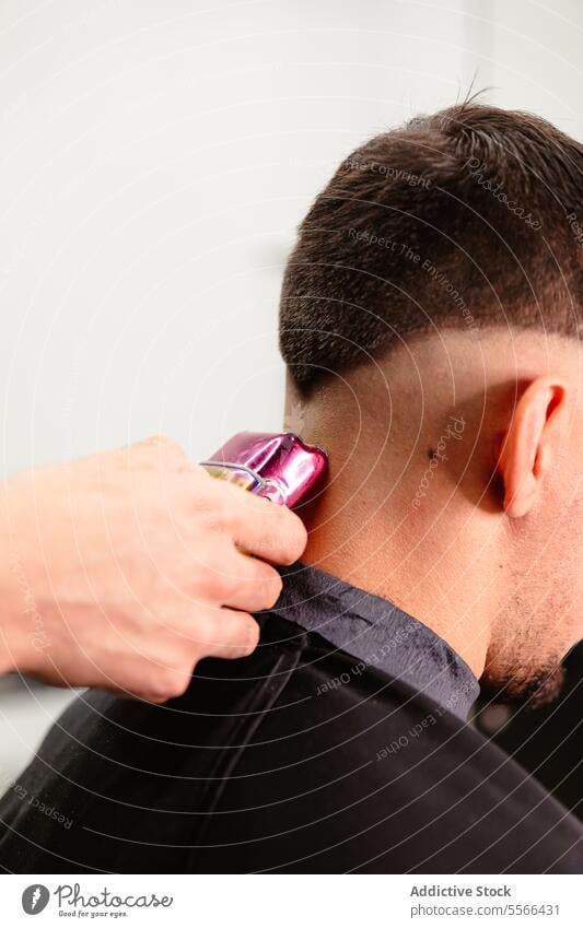 Close-up trim with purple electric clipper on nape. Barber close-up male hand salon hair precision care man caucasian grooming detail equipment styling modern