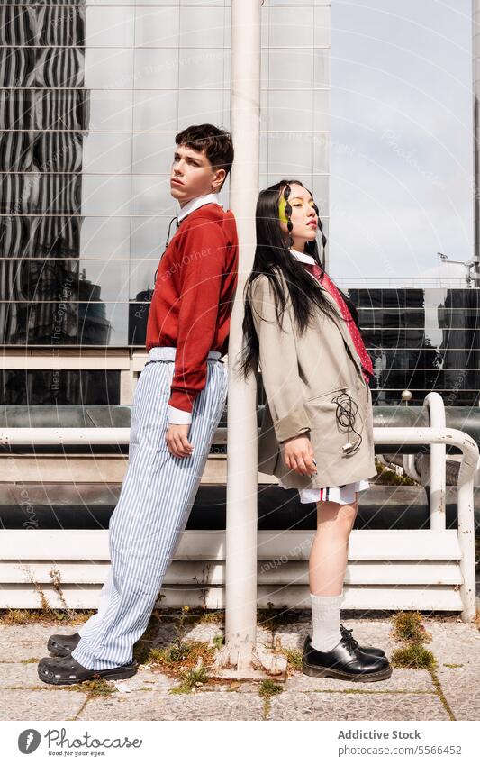 Fashion portrait of Gen-Z duo with cables in front of contemporary urban buildings. fashion outdoors work modern pose style male female casual coat sweater