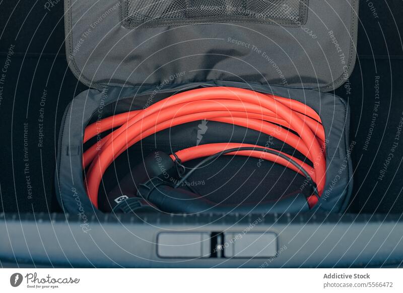 Electric vehicle charging cable in trunk electric orange storage bag gray coiled car equipment EV transport plug connector power energy eco-friendly sustainable
