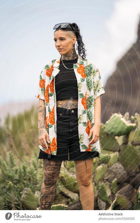 Smiling tattooed woman standing on blurred cactus stylish nature enjoying attractive young fashion female pretty style cool beauty trendy casual youth leisure