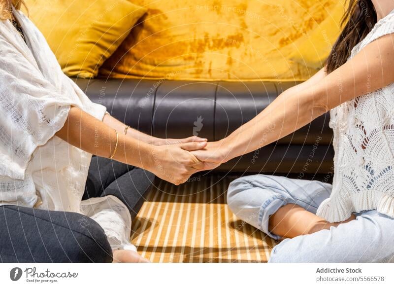 A couple of anonymous women shaking hands psychological therapy emotional support conversation sitting together talk counseling mental health wellness