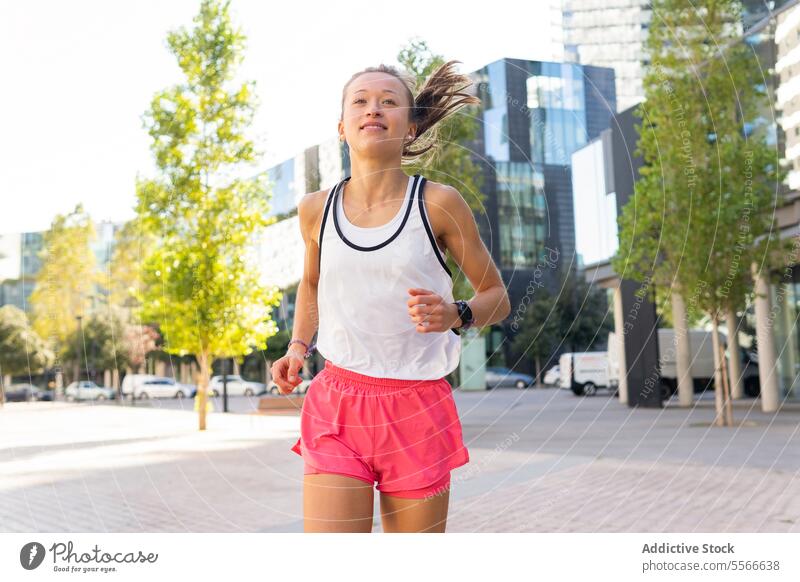 A woman running down a sidewalk in a city urban fitness sport active metropolitan lifestyle jungle exercise pavement jog runner downtown activity health