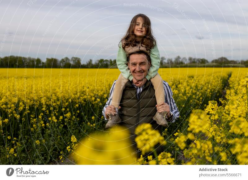 Father-daughter moment in a yellow bloom field. father flower carry shoulder joy family bond love nature portrait outdoor happiness smile happy together meadow