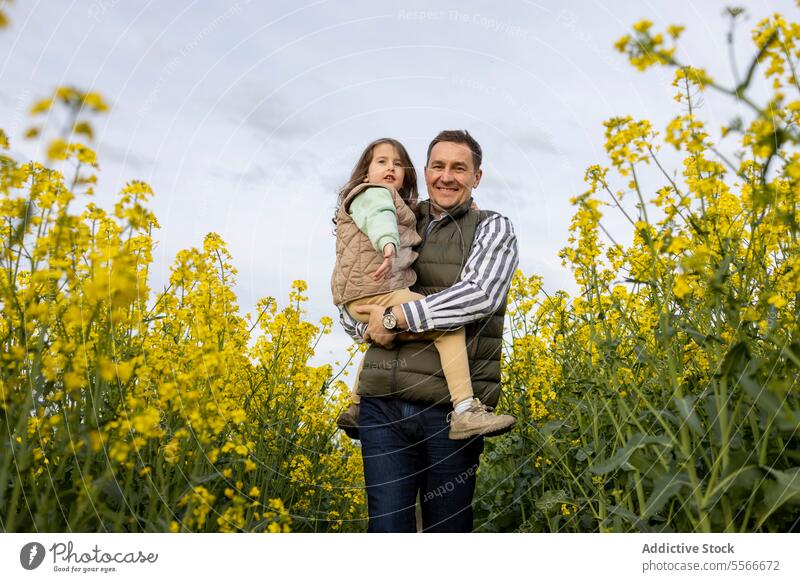 Father and daughter enjoying time in yellow flower field. father bond family happiness rap nature parent child portrait love outdoor togetherness bloom smile