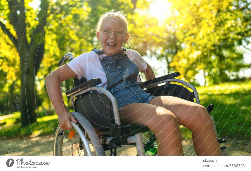 Happy young handicapped blond girl sit in wheelchair during walk in park, teenager disability concept image happy paralysis care physical help support therapy
