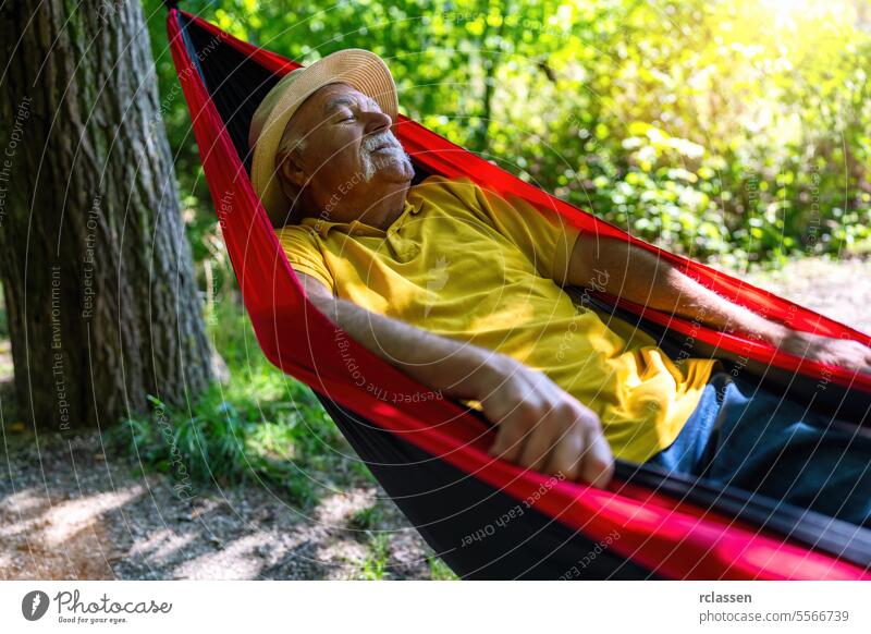 Elderly Man with straw hat Relishing a Peaceful Nap in a Hammock in the park grandfather hammock elderly man relaxation nature peaceful nap forest outdoors